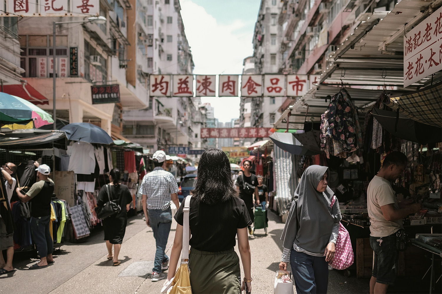 A woman walking down Apliu Street Market in Hong Kong. We take a look at the trend of wanting to "live like a local" when traveling.
