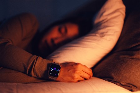 Close-up of a woman sleeping with a smartwatch tracking her sleep data. Here's what the science says about sleep and aging.