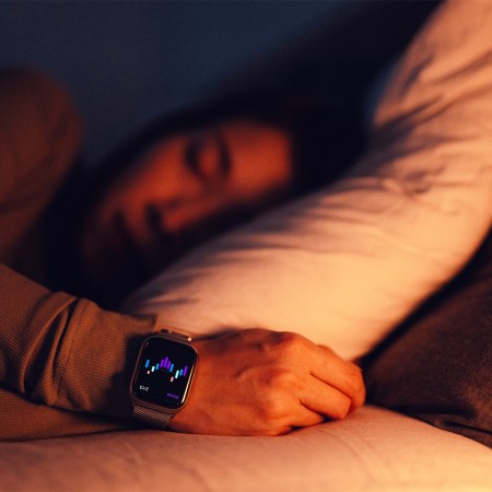 Close-up of a woman sleeping with a smartwatch tracking her sleep data. Here's what the science says about sleep and aging.