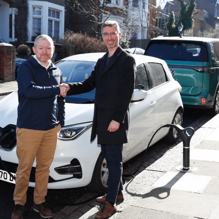 Camden Council and Trojan Energy representatives shaking hands with an EV charger behind them
