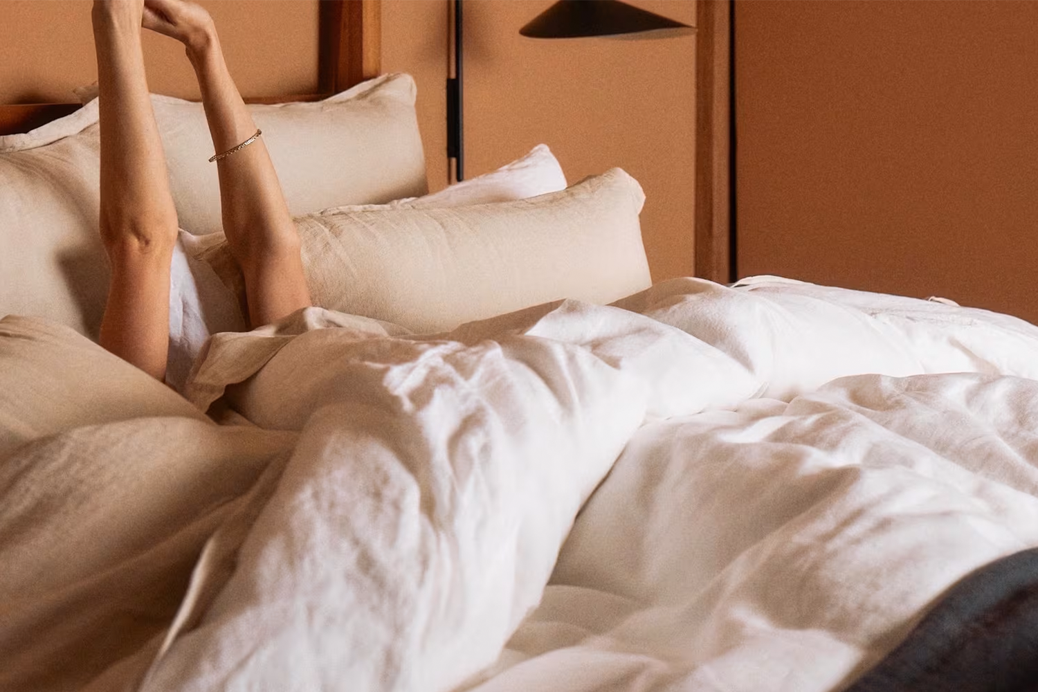 A person laying in linen sheets from bedding brand Parachute