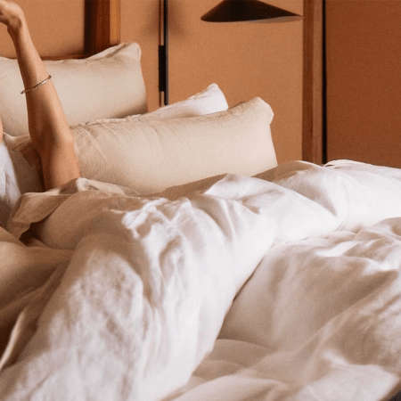 A person laying in linen sheets from bedding brand Parachute