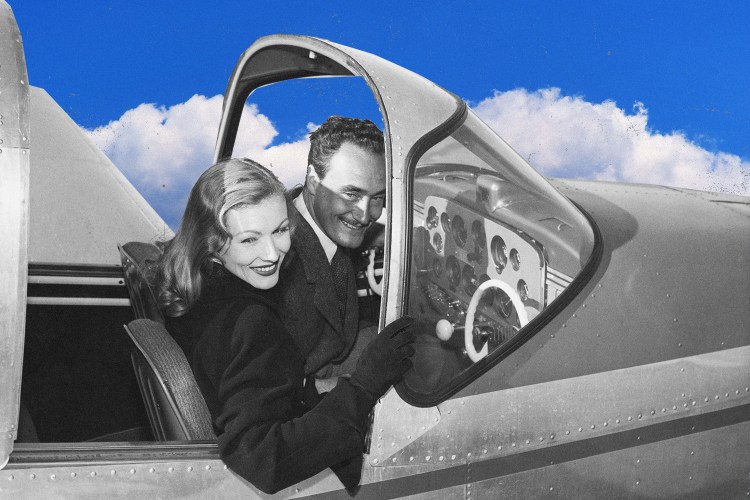 Black-and-white vintage photo of a smiling couple in the open cockpit door of a small airplane, composited against a bright blue sky with clouds. The woman, in the foreground with wavy shoulder-length hair and a dark coat, leans back against the man behind her, who wears a suit and tie. Her gloved hand rests on the plane's window frame near the instrument panel.
