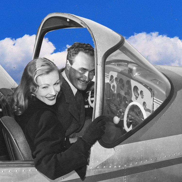 Black-and-white vintage photo of a smiling couple in the open cockpit door of a small airplane, composited against a bright blue sky with clouds. The woman, in the foreground with wavy shoulder-length hair and a dark coat, leans back against the man behind her, who wears a suit and tie. Her gloved hand rests on the plane's window frame near the instrument panel.