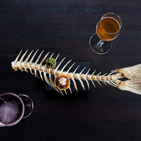 A fishbone serving platter with two hors d'oeuvres and two beers