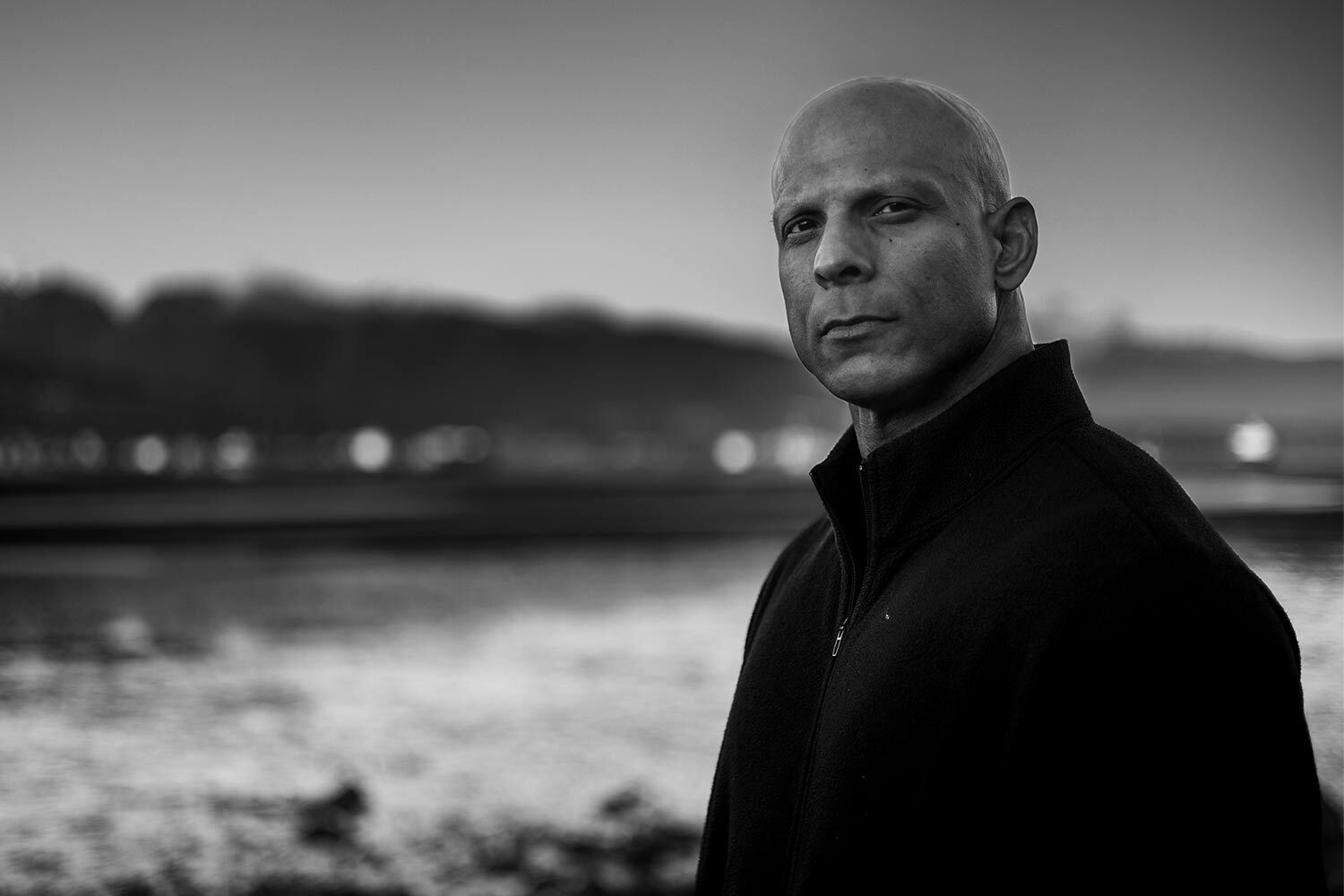 Sachin Latti in a black jacket, standing by the water in British Columbia ahead of his cross-Canada charity run