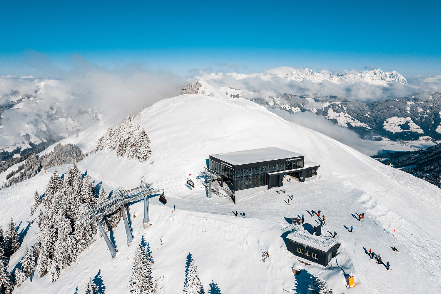 Aerial view of skiers gathering outside a modern lift station at SkiWelt, Austria.