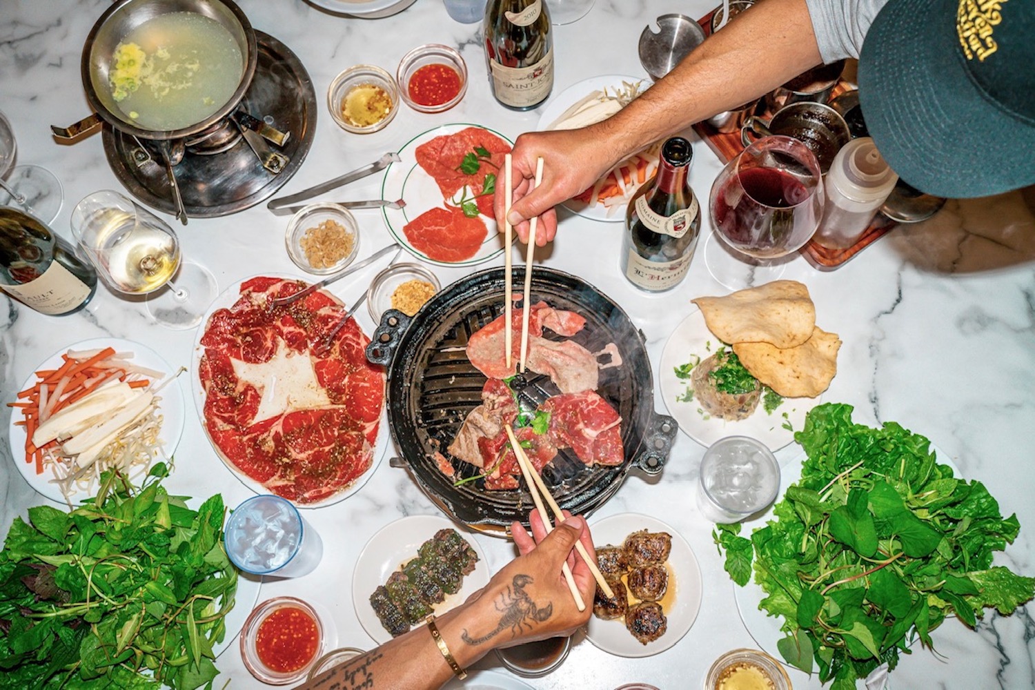 two people holding chopsticks eating steak off the grill in a korean bbq restaurant
