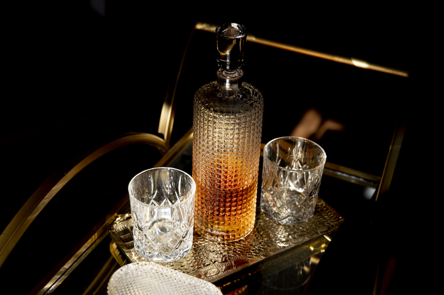 Whisky decanter and two crystal glasses on a brass bar cart