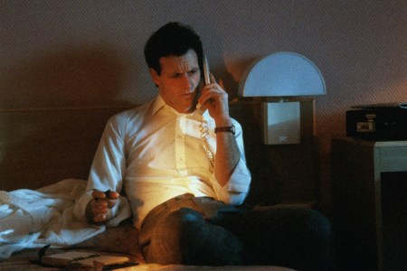 Businessman using phone in hotel room,open personal organiser on bed