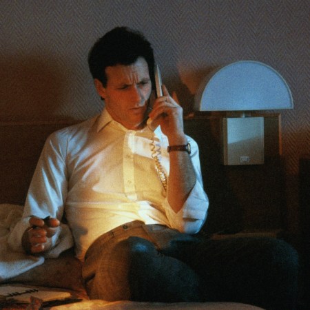 Businessman using phone in hotel room,open personal organiser on bed