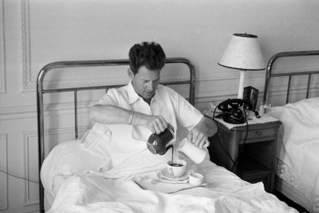 Man in bed pouring coffee and milk simultaneously with both hands