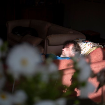 Man sleeping on sofa in his living room. We asked sleep experts about people who have sleep anxiety in a bed, but can sleep fine on a couch.