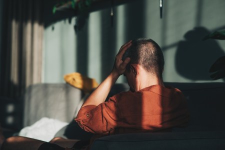 Man with headache sitting in the shadows