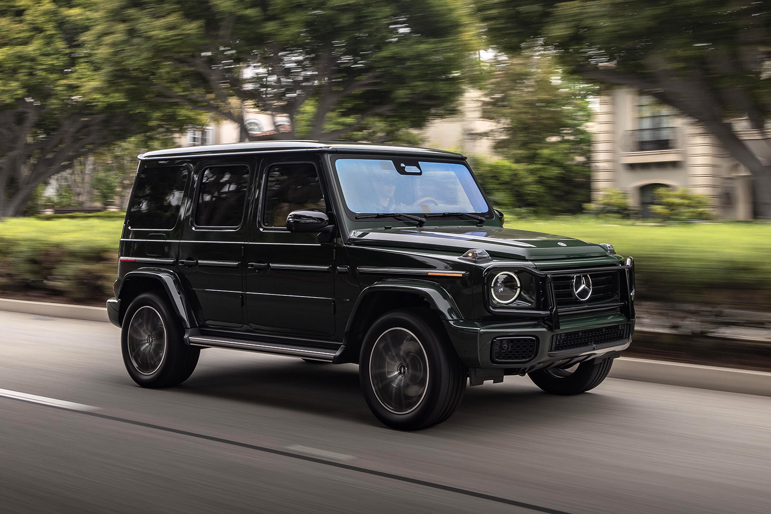 The new 2025 Mercedes-Benz G-Class driving down a tree-lined street