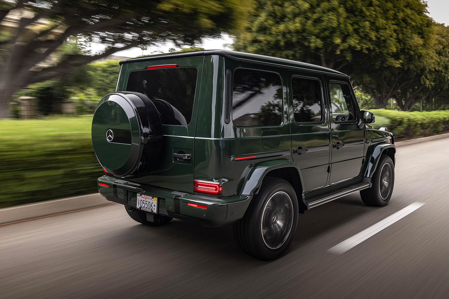 The rear end of the new 2025 Mercedes-Benz G-Class SUV as it drives away down a tree-lined road