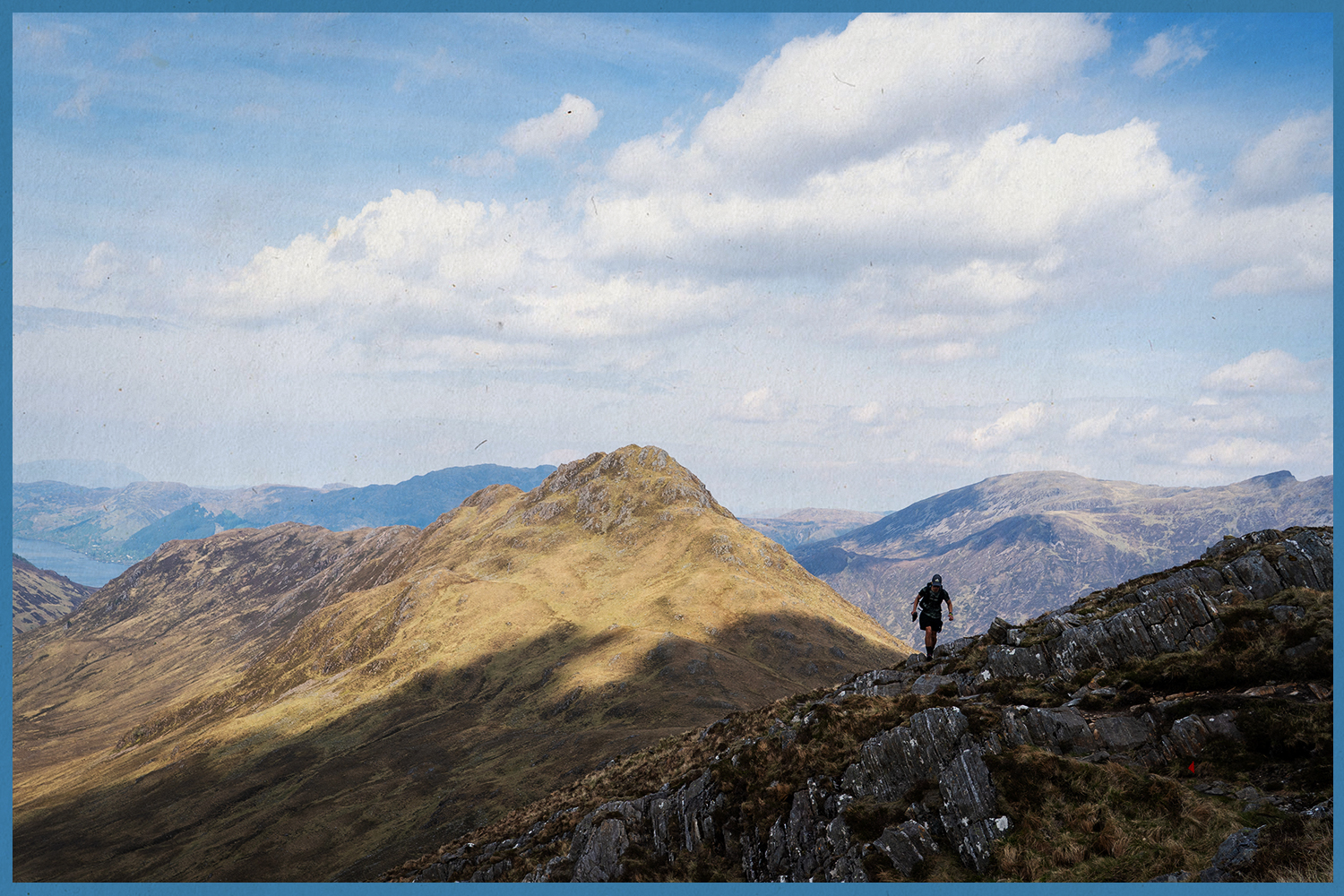 A lone trail runner climbs through the Scottish Highlands.