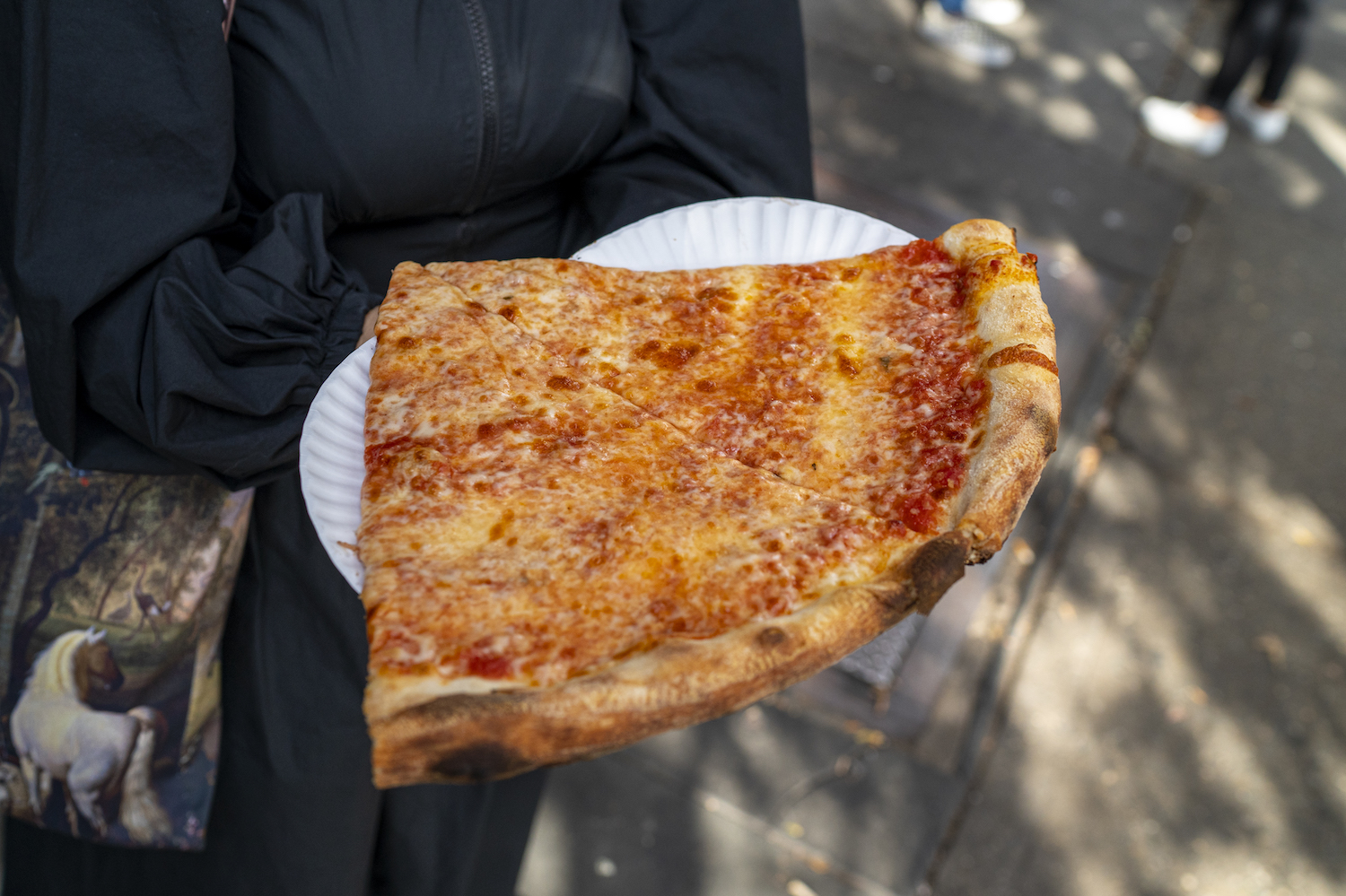 A tourist carries freshly made pizza slices from Joe's Pizza on Carmine Street