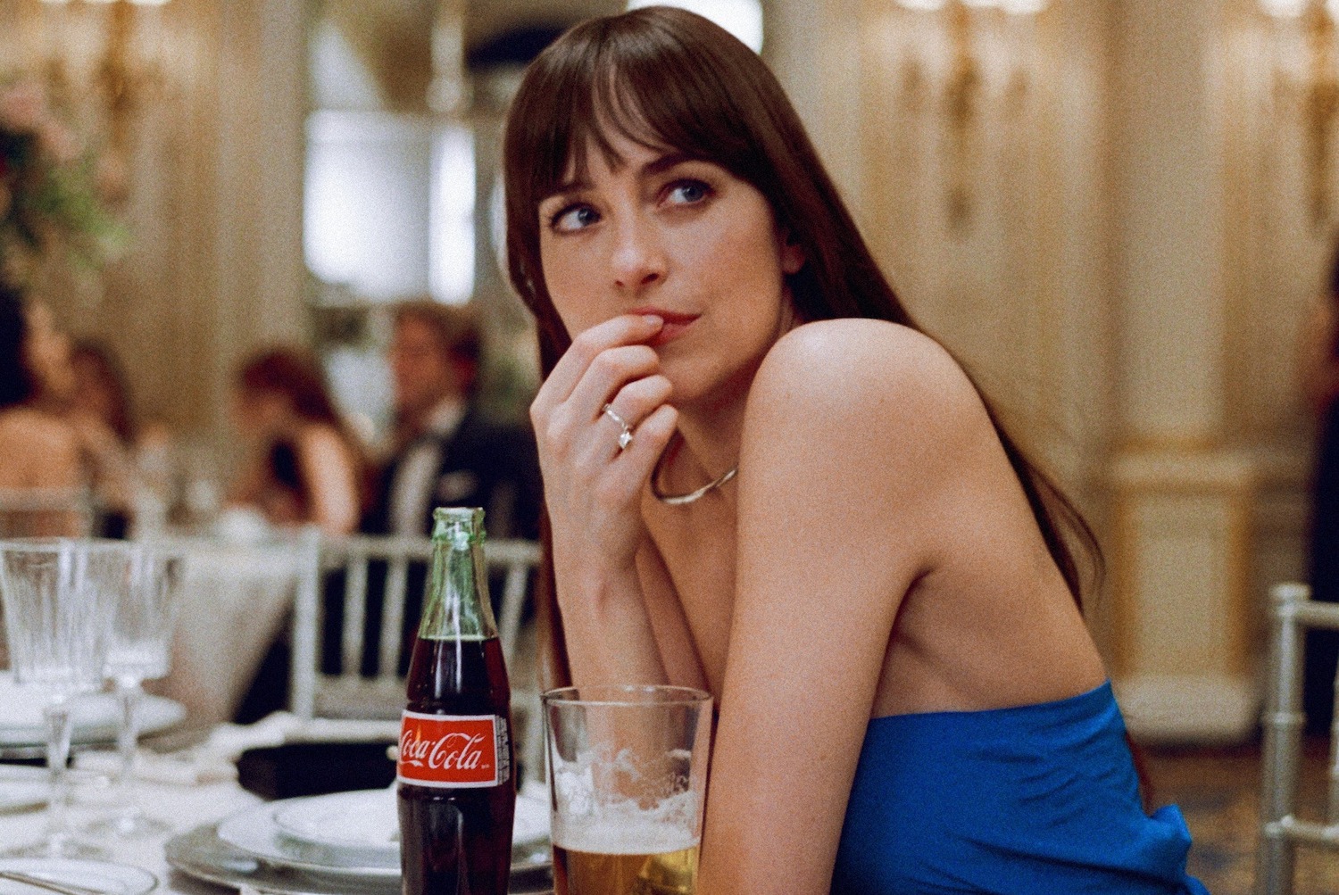dakota johnson in a blue dress with a coke and beer from the materialists