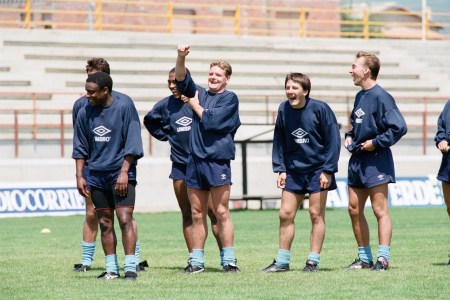 Group of soccer players in vintage Umbro training gear laughing and smiling during practice on a sunny field