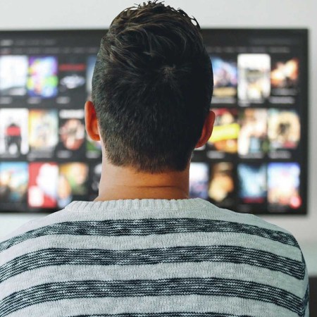 Young man staring at large TV screen full of movie choices