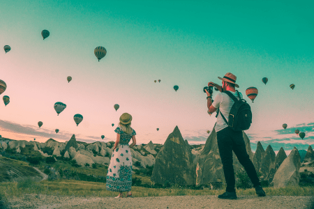 A photographer taking a picture of an influencer in front of a sky of hot air balloons