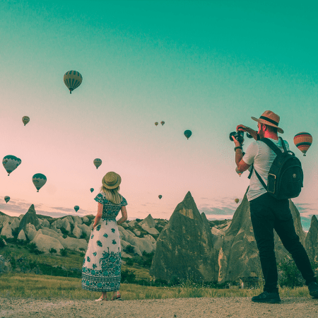 A photographer taking a picture of an influencer in front of a sky of hot air balloons