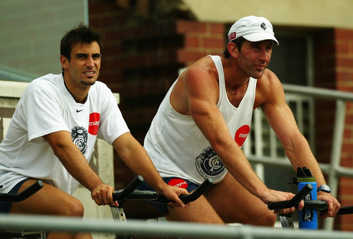 A pair of rugby players on exercise bikes.