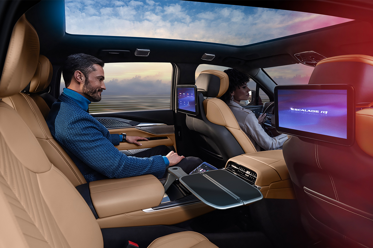 A man sitting in the backseat of the Escalade iQ while a woman sits in the driver's seat