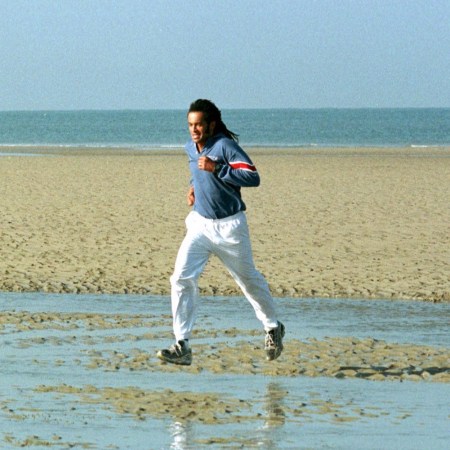 Man jogging on a beach in athletic gear, symbolizing the mental health and brain benefits of aerobic exercise.