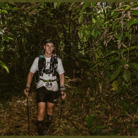 Runner trekking through dense Peruvian jungle with poles.