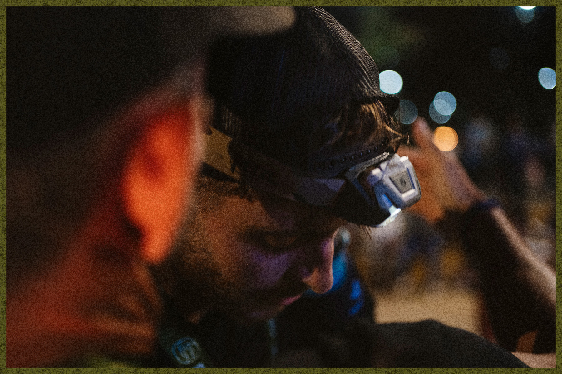 A runner with a headlamp, peering down as nightfall approaches.