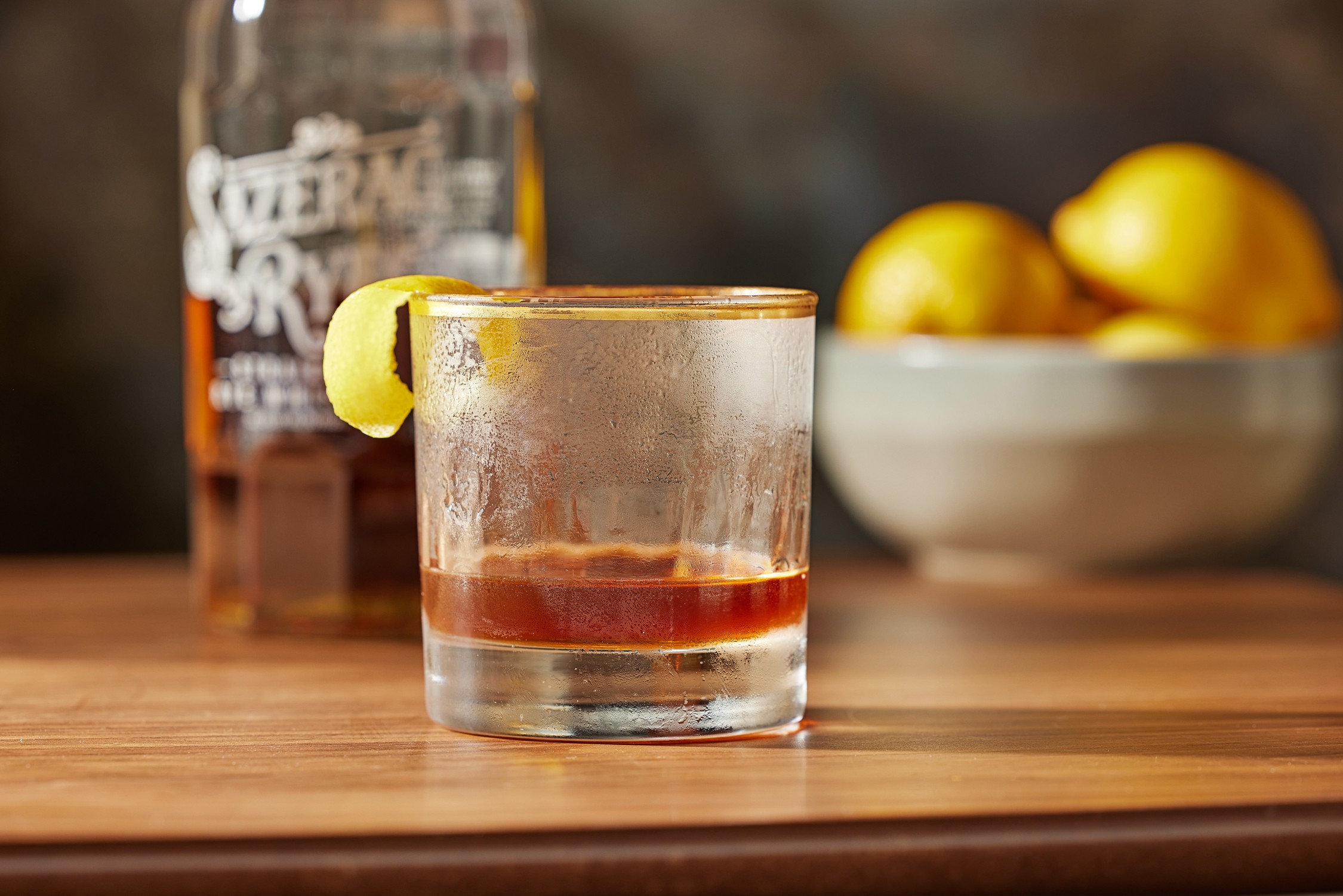 a sazerac cocktail on a table in front of a Bottle of Sazerac