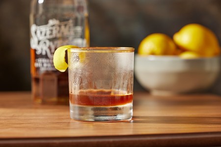 a sazerac cocktail on a table in front of a Bottle of Sazerac