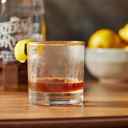 a sazerac cocktail on a table in front of a Bottle of Sazerac