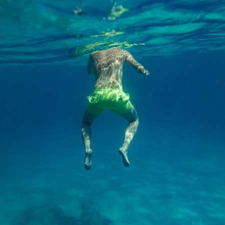 Person treading water in a lake, viewed from below the surface