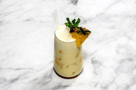 A cocktail ''Pina colada'' is sitting on a bright background