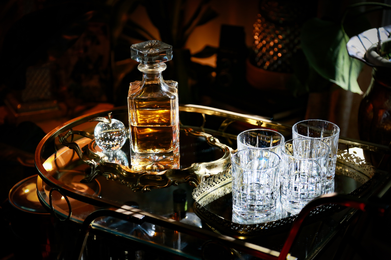 Photograph of a decanter of cask-strength bourbon and glasses sitting on a vintage bar cart in color