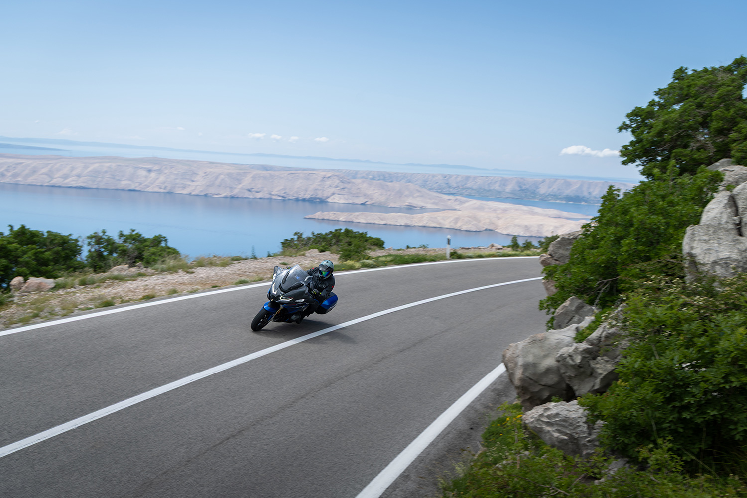 A rider on a BMW motorcycle driving along the Adriatic Highway in Croatia