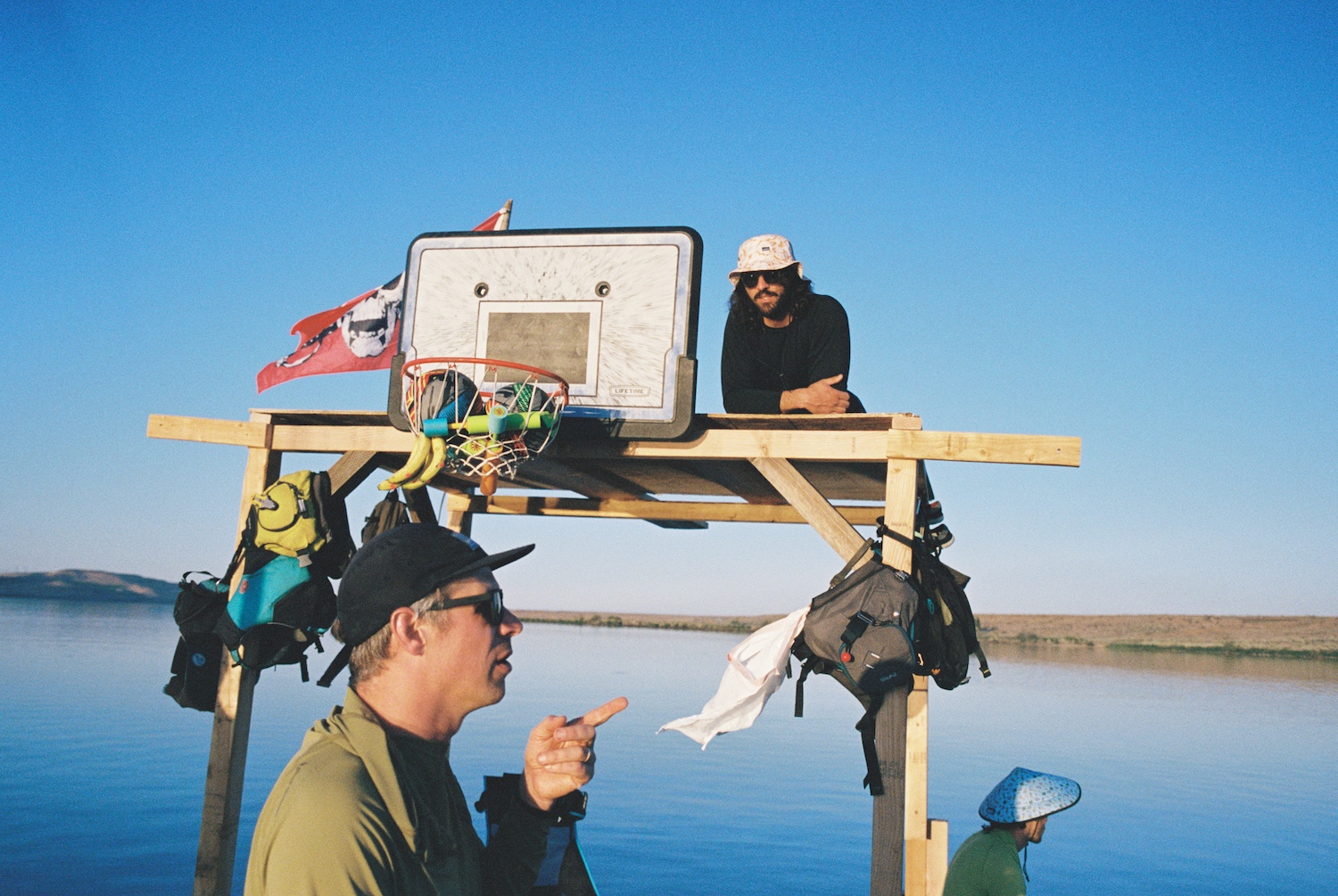 Two men on the makeshift raft, with a view of their DIY basketball hoop.