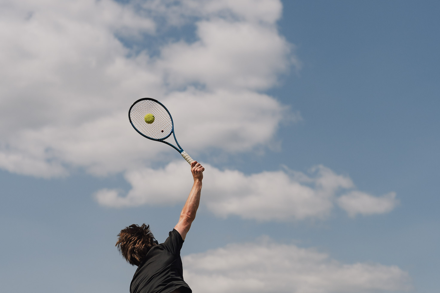A man serving a ball outside.