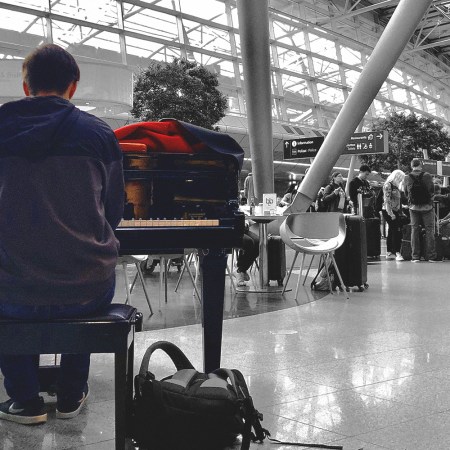 Airport musician in color against a B&W background of the airport