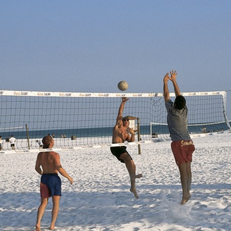 Three men playing beach volleyball