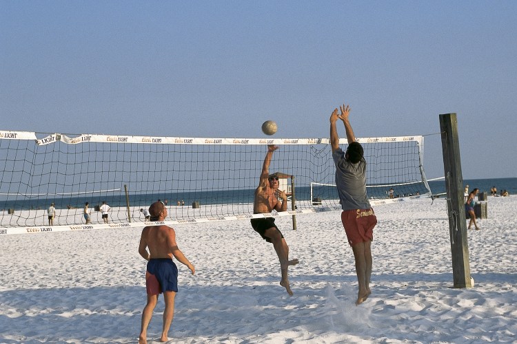 Three men playing beach volleyball