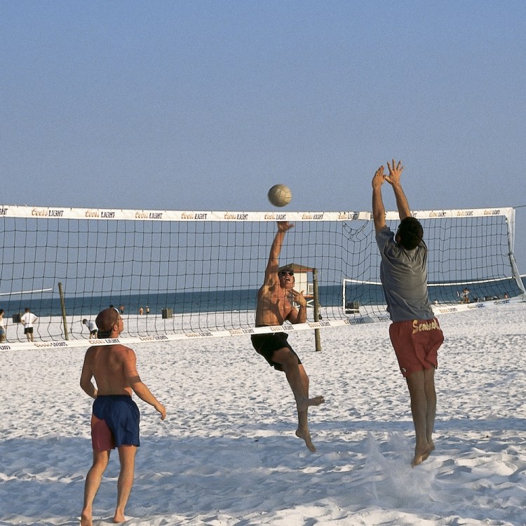 Three men playing beach volleyball
