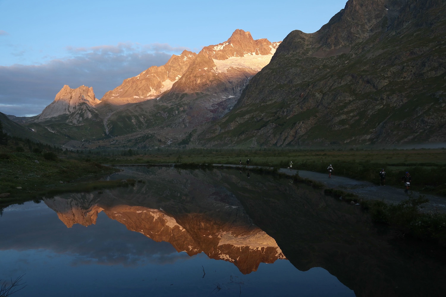 A view of runners competing in UTMB next to a lake.
