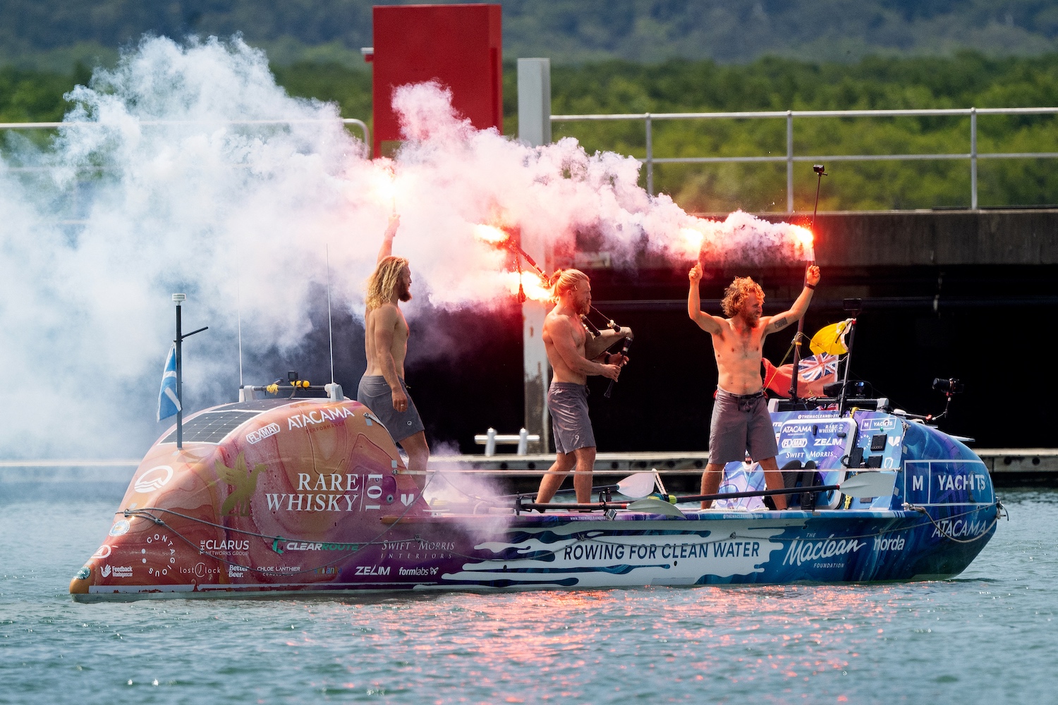 The three Maclean brothers Jamie, Ewan and Lachlan in an ocean rowboat, lighting celebratory flares.