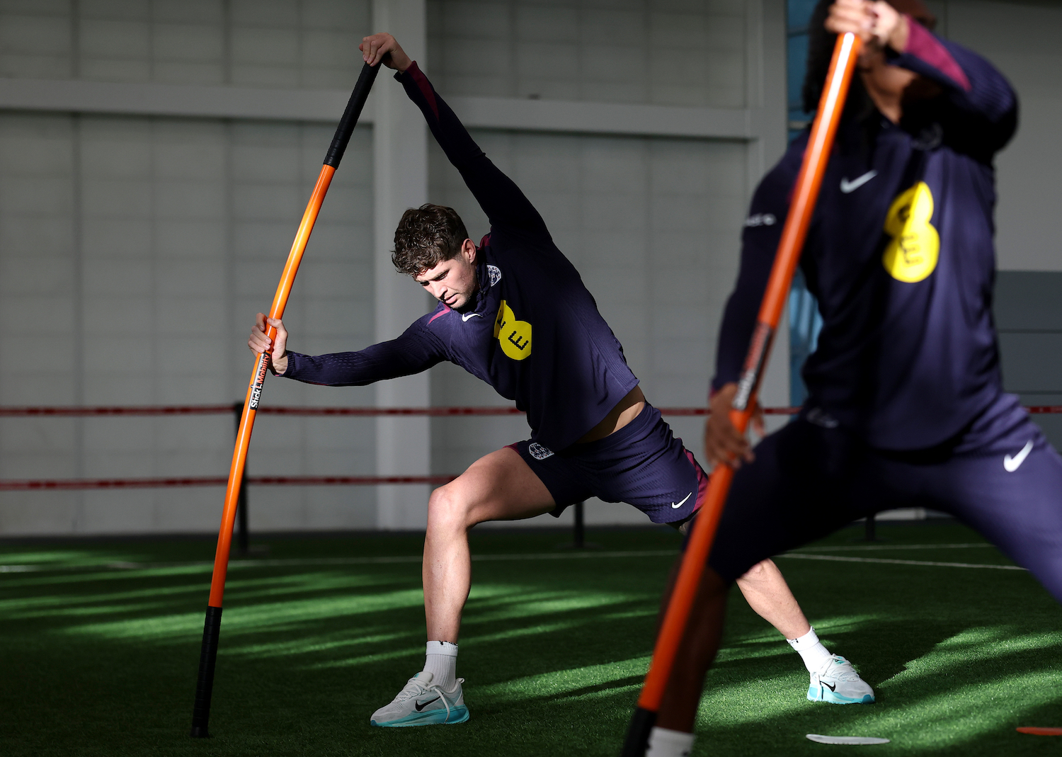 Some soccer players stretching with a weighted stick.