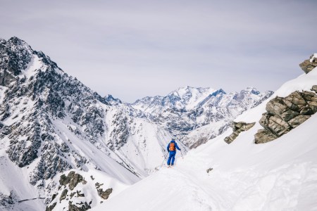 A skier on a narrow path with the Andes mountains in the background at Portillo, the legendary ski resort in Chile
