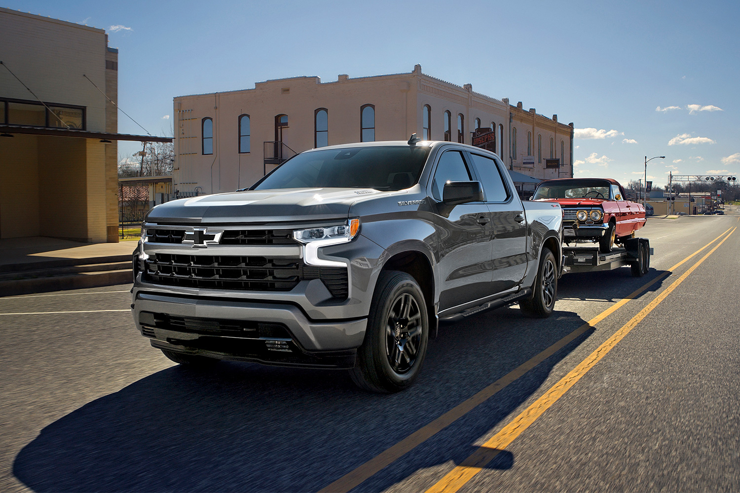 A Chevrolet Silverado truck towing a classic car on a trailer